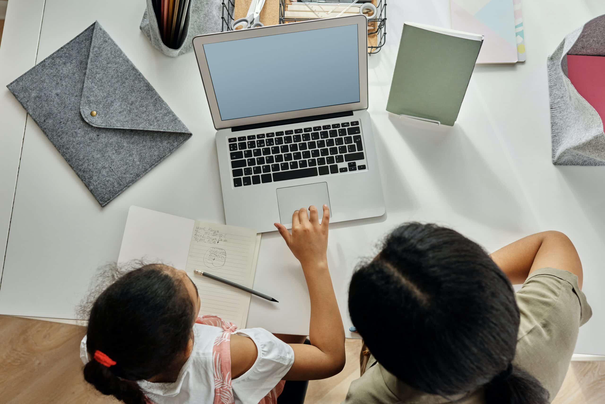 parent helping child with homework at computer, top down view