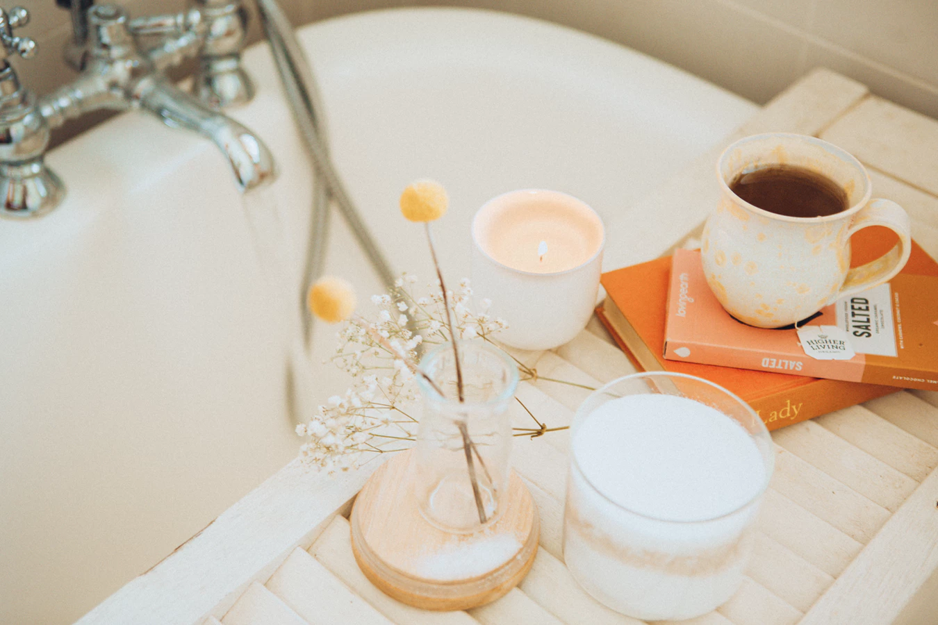 Bath tub with tea, a book, and candles