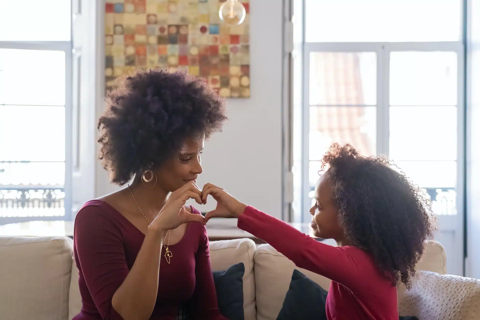 a mother and a daughter forming a heart shape with their hands