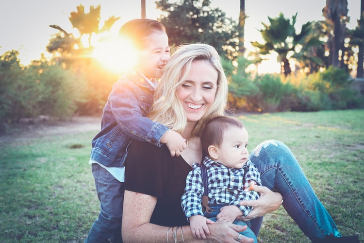 a blonde woman with her two young sons smiles