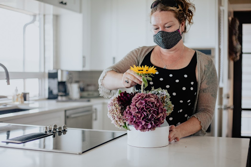 masked woman arranging flowers in a vase